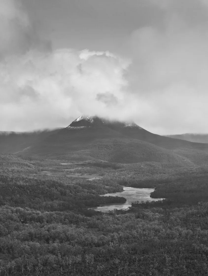 A monochrome view of a mountain under low clouds